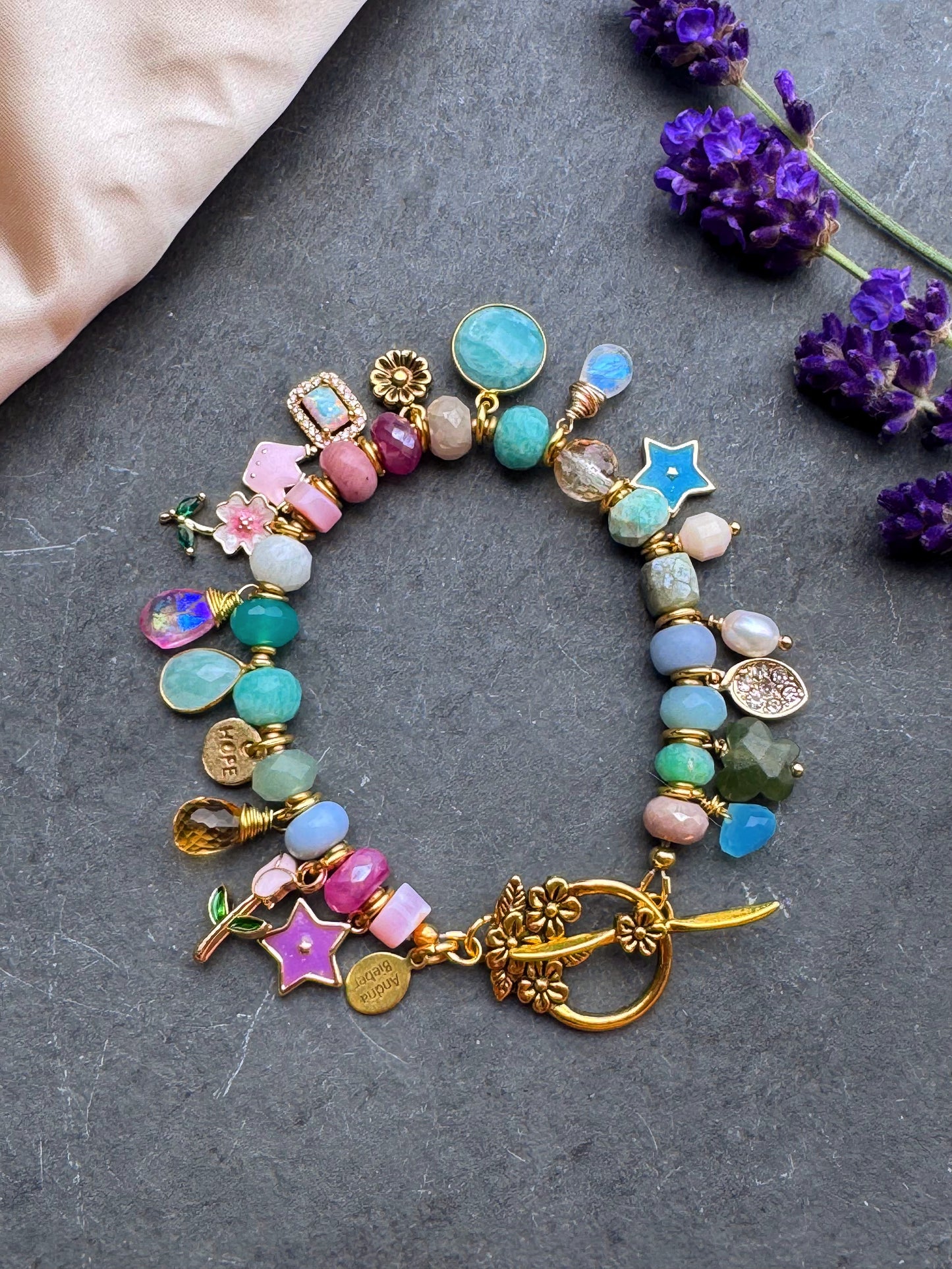 Charm pastel bracelet. Mixed gemstone, charms and gold metal bracelet.